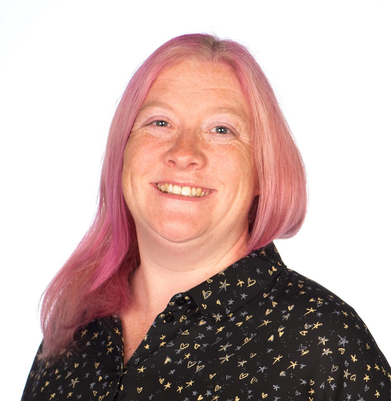 A smiling person with long pink hair, wearing a black shirt.